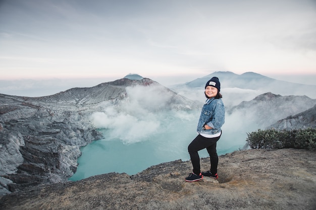 счастливая женщина стоит на вершине Kawah ijen