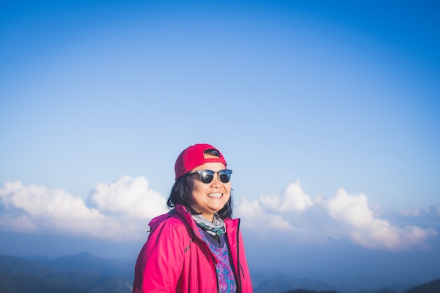 幸せな女は、霧と雲の景色を見ている山の上に立ちます。