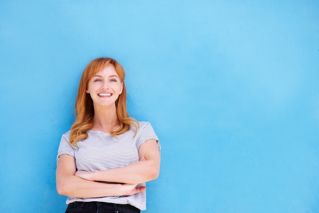 Happy woman standing against blue wall