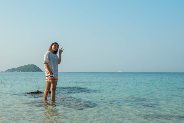 海のビーチで腕を伸ばして立っている幸せな女性