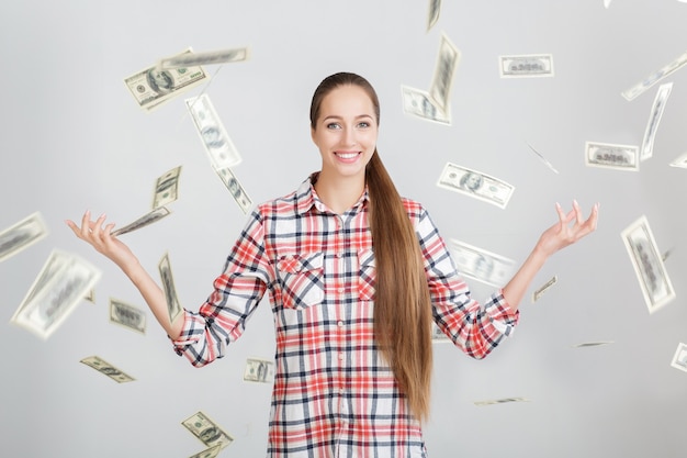 Happy woman standing under money rain