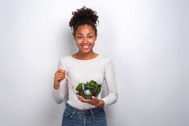 Happy woman standing with bowl of salad over wite 