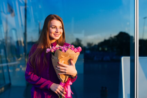 Happy woman stands with pink roses on contarst background