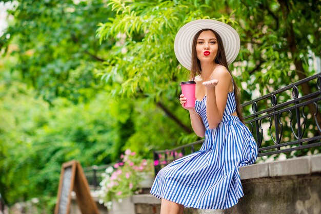 麦わら帽子でポーズをとって夏のドレスで幸せな女性