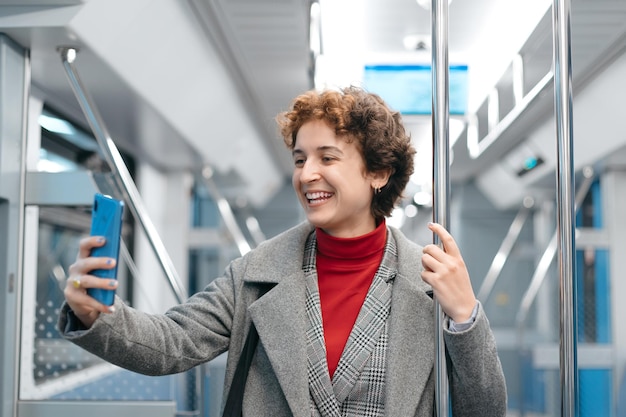 空の地下鉄車に立って自撮りをしている幸せな女