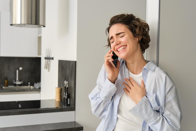 Happy woman talking on mobile phone laughing and smiling with eyes closed having nice friendly conve