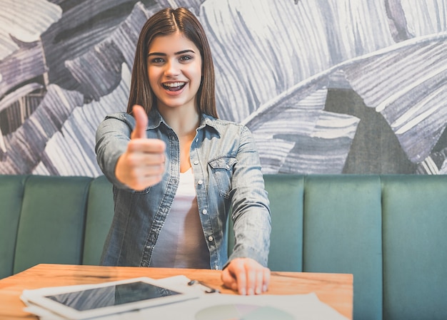 The happy woman thumbs up at the table