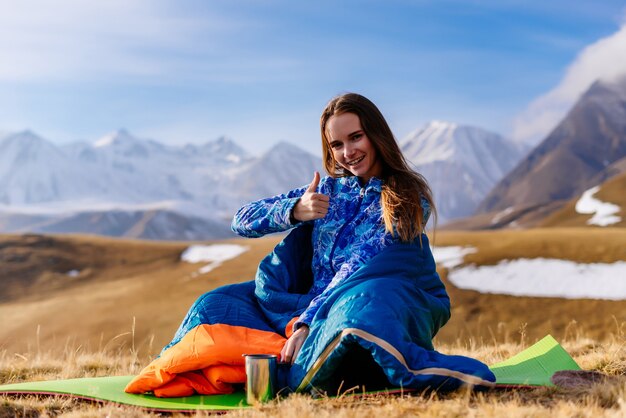 Turista felice si siede sullo sfondo delle montagne