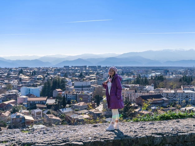 Счастливая туристка, стоящая на смотровой площадке с видом на городской пейзаж Кутаиси с ясным голубым небом с холма собора Баграти в Грузии осенью