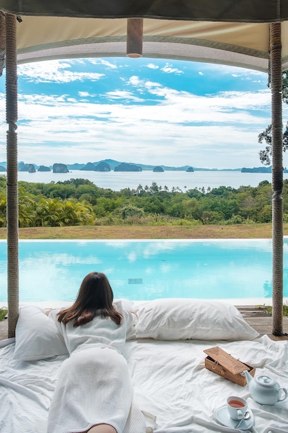 Счастливая женщина-путешественница наслаждается прекрасным видом на океан. Турист отдыхает на тропическом роскошном курорте с бассейном.