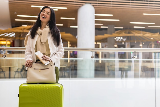 Happy woman traveler with documents and ticket waiting departure at international airport terminal