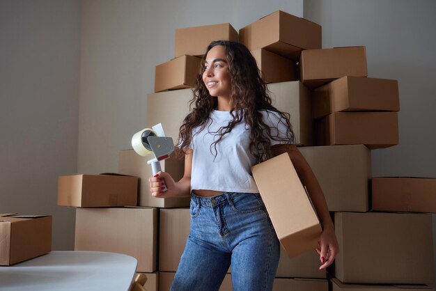 Happy woman unpacking container at home opening carton box looking inside package Smiling satisfied customer receiving parcel from order delivery service unboxing purchase