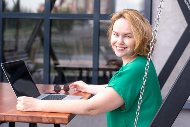 Happy woman using application on digital laptop in a street cafe