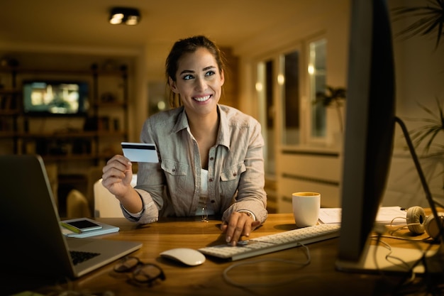 Happy woman using computer and credit card for shopping on the internet at home