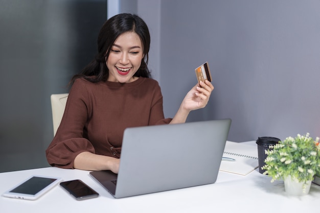 Счастливый женщина, используя портативный компьютер для онлайн-покупок с помощью кредитной карты