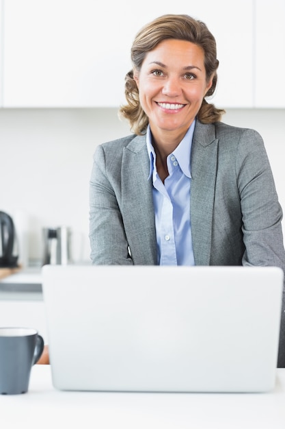 Photo happy woman using laptop in kitchen