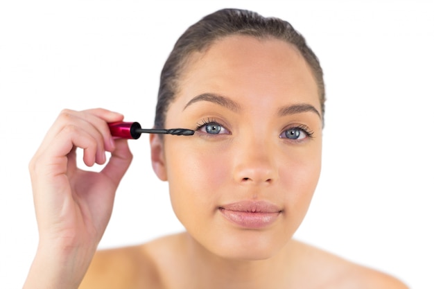 Happy woman using mascara for her eyelashes