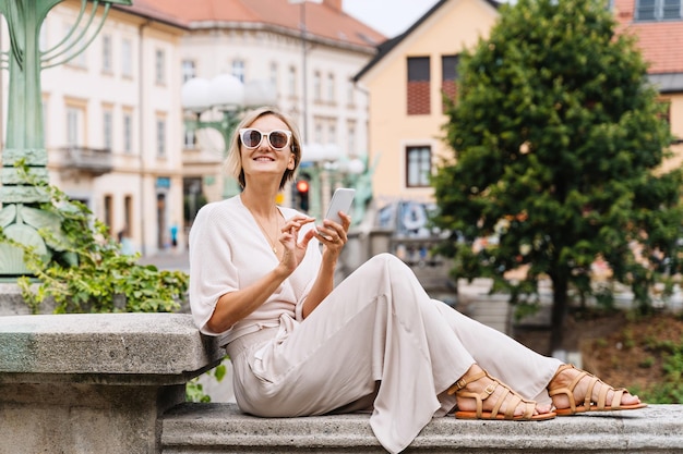 Photo happy woman using smart phone on the street of european city modern lifestyles of urban people