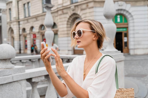 ヨーロッパの街でスマートフォンを使っている幸せな女性 都市人の現代的なライフスタイル