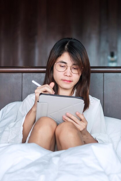 Happy woman using tablet for social media young female watching\
movies on computer pad on bed at home technology network online\
shopping e commerce lifestyle and digital communication\
concept