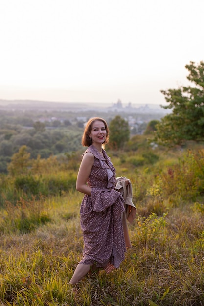 Happy woman walks at sunset on a hill overlooking the river