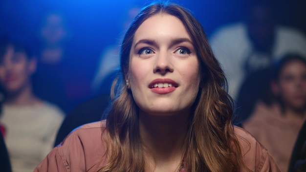 Happy woman watching movie in cinema Cheerful girl eating popcorn on funny film