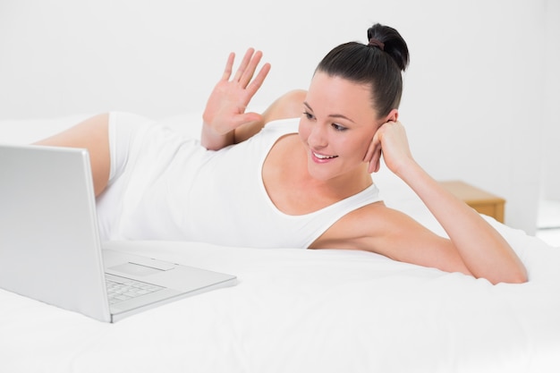 Happy woman waving hand at laptop screen