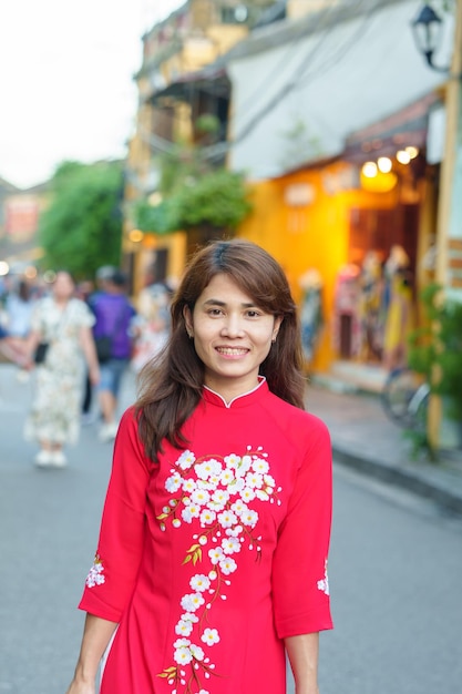 Happy woman wearing Ao Dai Vietnamese dress asian traveler sightseeing at Hoi An ancient town in central Vietnam landmark and popular for tourist attractions Vietnam and Southeast travel concept