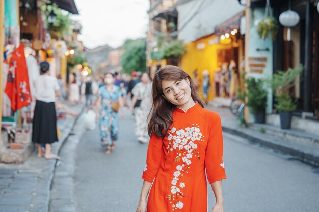 Happy woman wearing Ao Dai Vietnamese dress asian traveler sightseeing at Hoi An ancient town in central Vietnam landmark and popular for tourist attractions Vietnam and Southeast travel concept