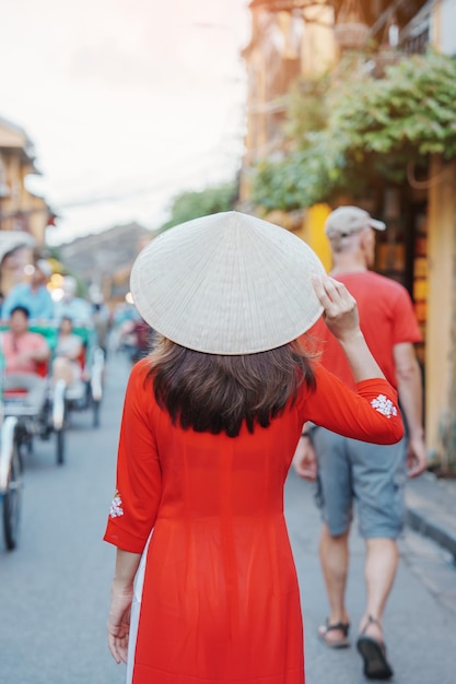 Happy woman wearing Ao Dai Vietnamese dress asian traveler sightseeing at Hoi An ancient town in central Vietnam landmark and popular for tourist attractions Vietnam and Southeast travel concept