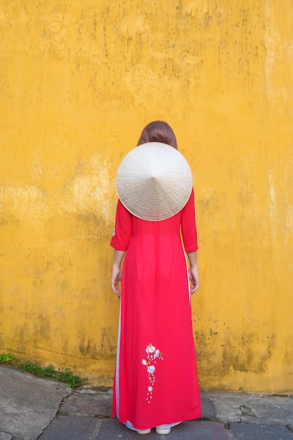 Happy woman wearing Ao Dai Vietnamese dress and hat traveler sightseeing at Hoi An ancient town in central Vietnam landmark and popular for tourist attractions Vietnam and Southeast travel concept