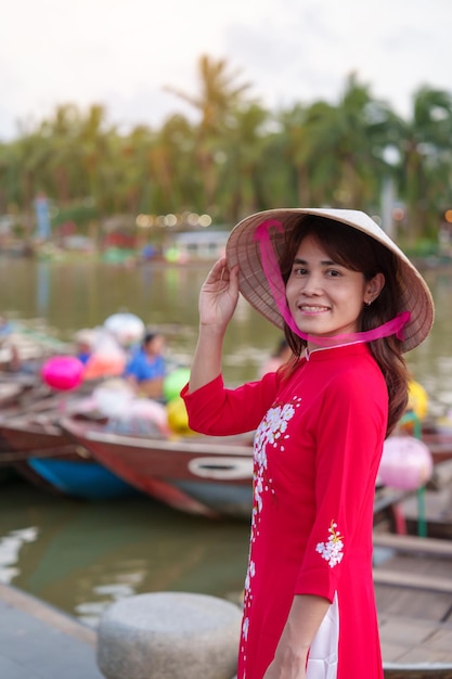 アオザイ ベトナム ドレス旅行者を着て幸せな女性は、ホイアンの古代の町のランドマークであるトゥボン川と観光ボートに乗って、観光名所ベトナムと南東部の旅行の概念を訪れます