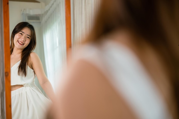 Happy woman wearing dress on front mirror looking clothes at home after morning wake up