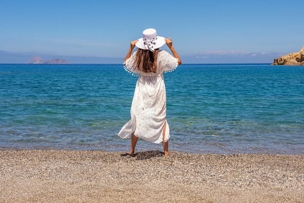 Happy woman wearing a hat on a tropical beach