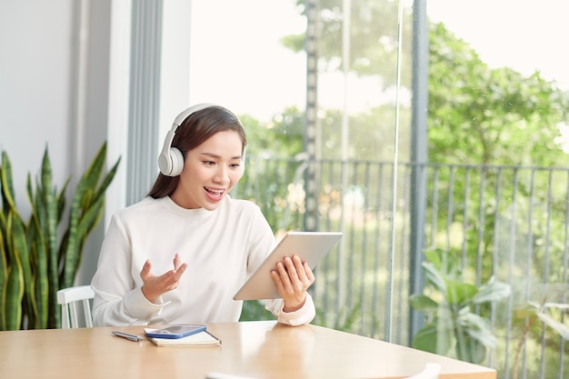 Happy woman wearing wireless headphones waving in video conference