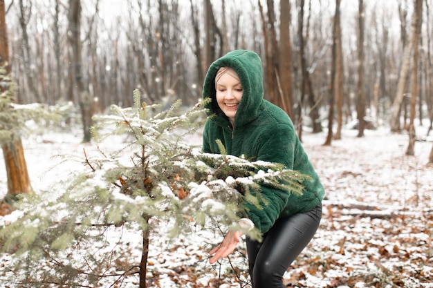 Happy woman in winter forest female portrait in snow park cheerful woman touch snow branches of litt