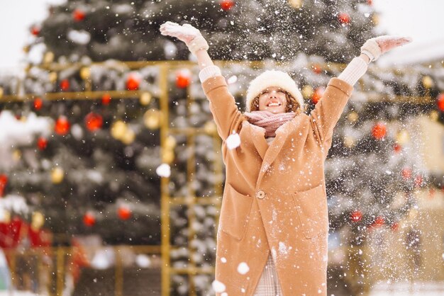 Счастливая женщина в зимней одежде на фоне гирляндных огней Зимние праздники моды