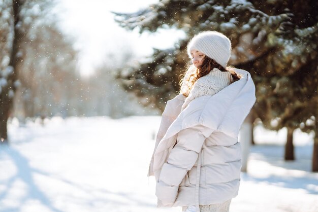 Happy woman in winter style clothes walking in the snowy park Nature holidays travel concept