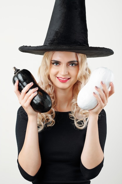 Foto donna felice in cappello della strega che mostra zuccini