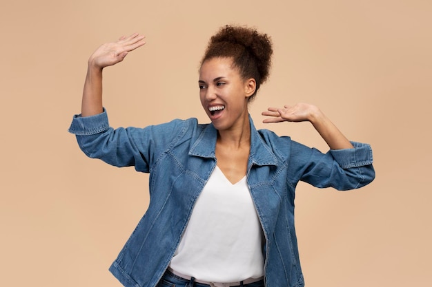 Happy woman with Afro hairstyle raised arms dancing celebrating