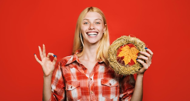 Happy woman with autumn wreath shows ok sign decorative thanksgiving wreath with maple leaf autumnal