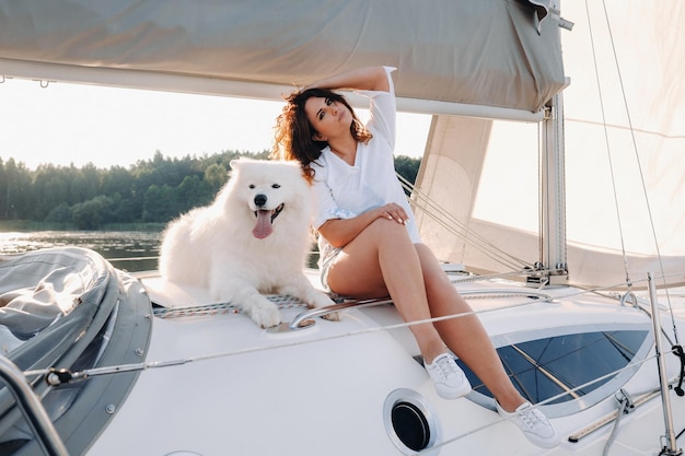 海の白いヨットに大きな白い犬と幸せな女性。