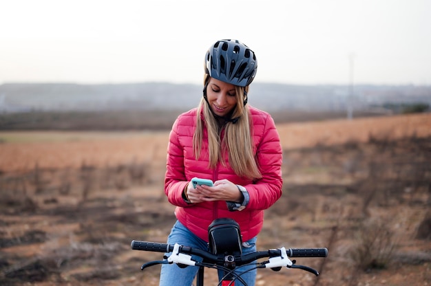 Photo happy woman with blonde hair consulting mobile phone in field