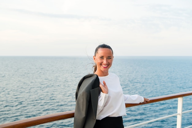 マイアミ、アメリカの船上でビジネスジャケットと幸せな女性。ビジネスのための旅行。青い海の船上で官能的な女性の笑顔。ファッション、美容、ルック。放浪癖、冒険、発見、旅。