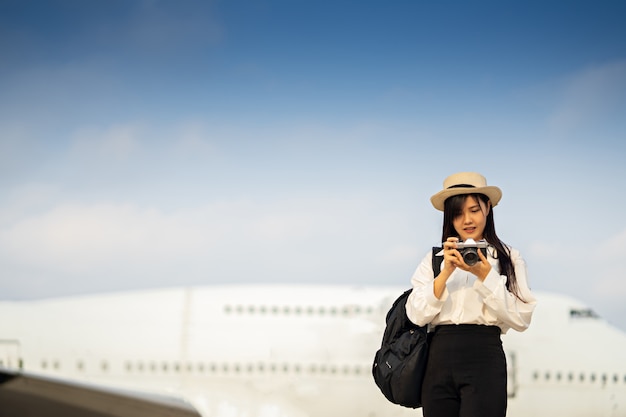 飛行機で旅行を待っているカメラで幸せな女。