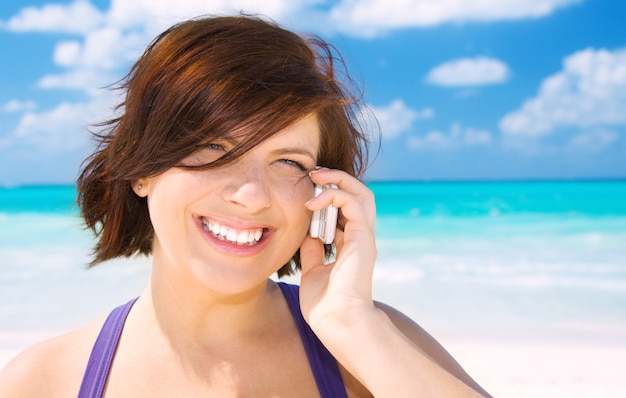 happy woman with cell phone on the beach