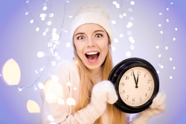 Happy woman with clock against blurred lights