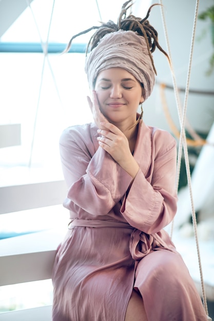 Happy woman with closed eyes sitting near window