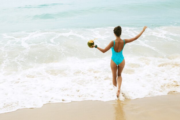 Happy woman with a coconut on the beach