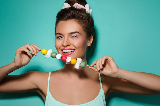 Happy woman with colorful makeup and sweet candies on skewer